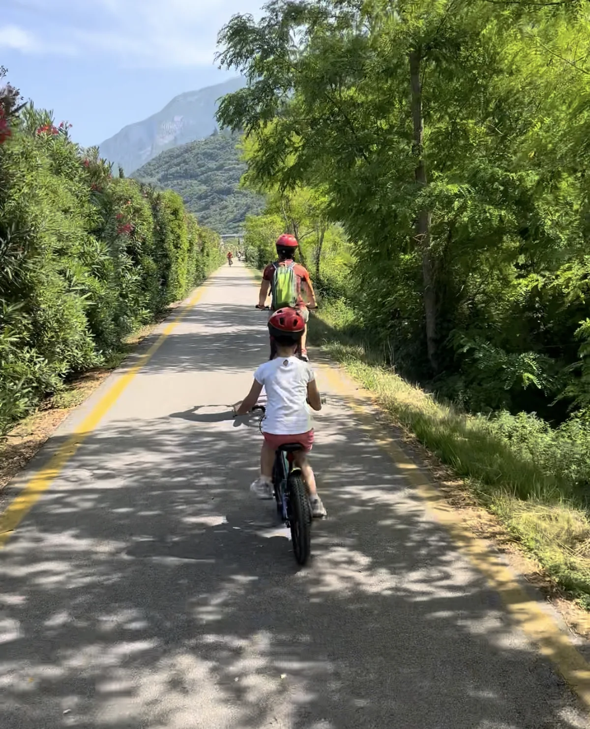 Mamma e bambina in bici sulla ciclabile asfaltata da Torbole ad Arco nella valle del Sarca, Lago di Garda