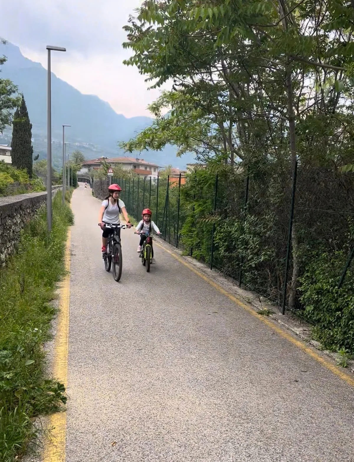 Mamma e bambina in bici sulla ciclabile del giro intorno al Monte Brione vicino a Riva del Garda